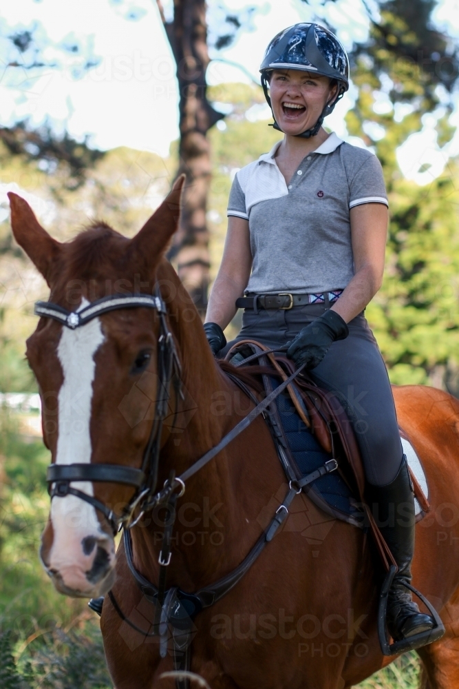 Happy young female rider atop horse - Australian Stock Image