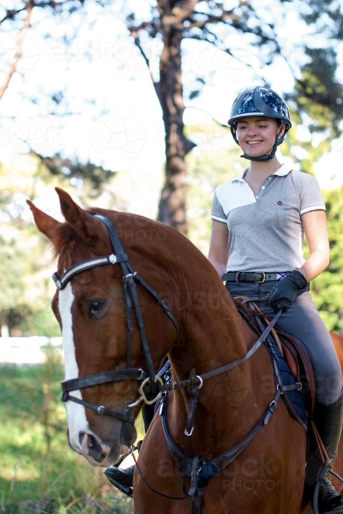 Happy young female rider atop horse - Australian Stock Image