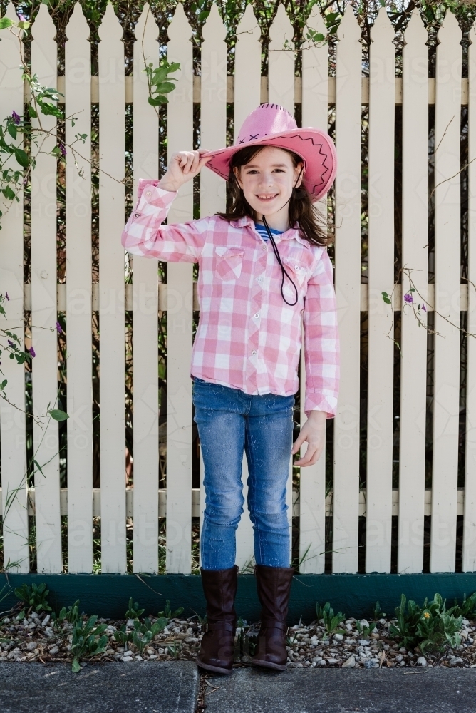 Happy young girl dressed up as a cowgirl wearing a pink akubra hat and pink and white shirt - Australian Stock Image