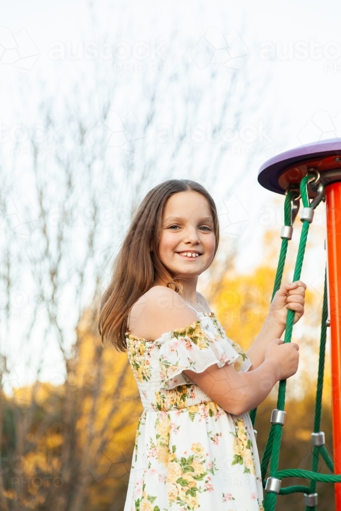 Happy young girl playing on equipment at park - Australian Stock Image