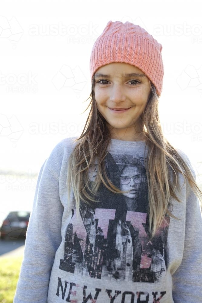 Happy young girl wearing beanie smiling at camera - Australian Stock Image