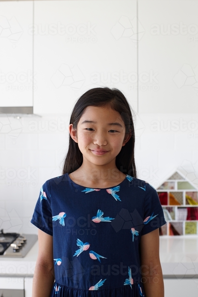 Happy young Japanese girl in kitchen - Australian Stock Image