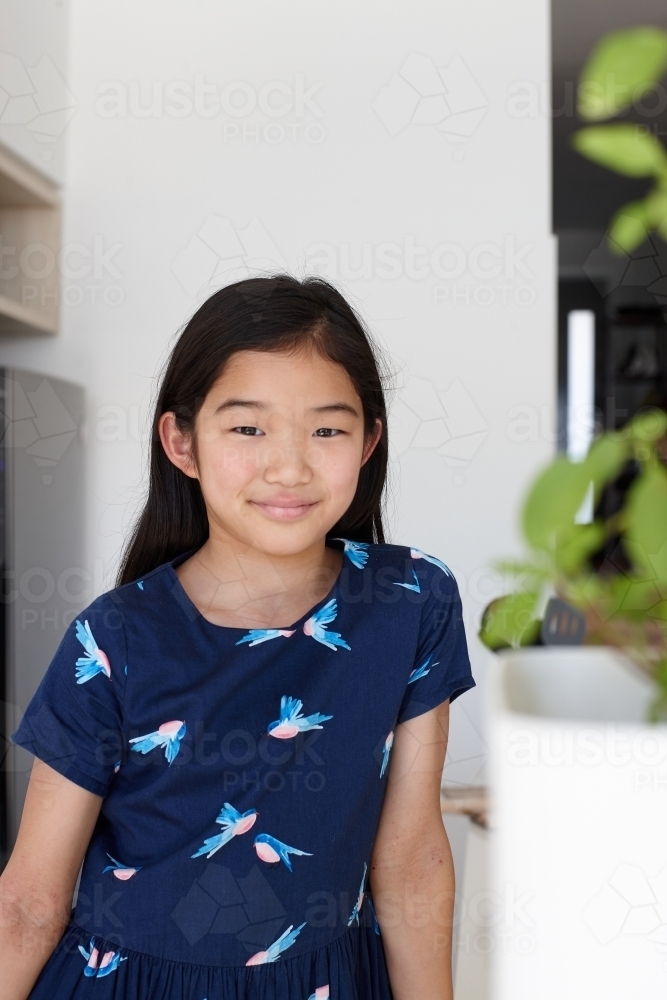 Happy young Japanese girl in kitchen - Australian Stock Image