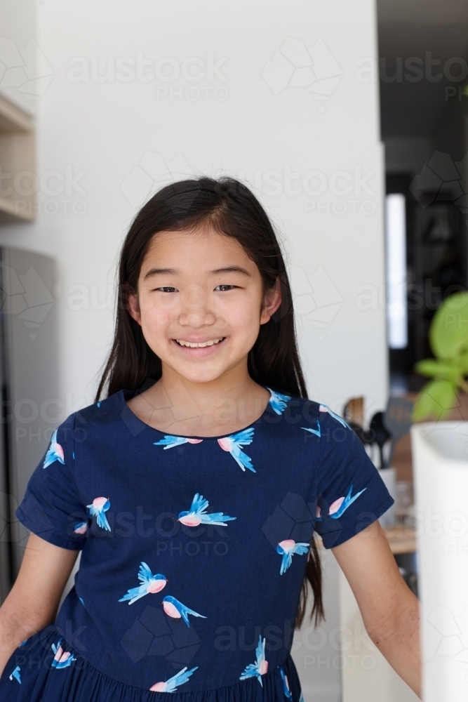 Happy young Japanese girl in kitchen - Australian Stock Image