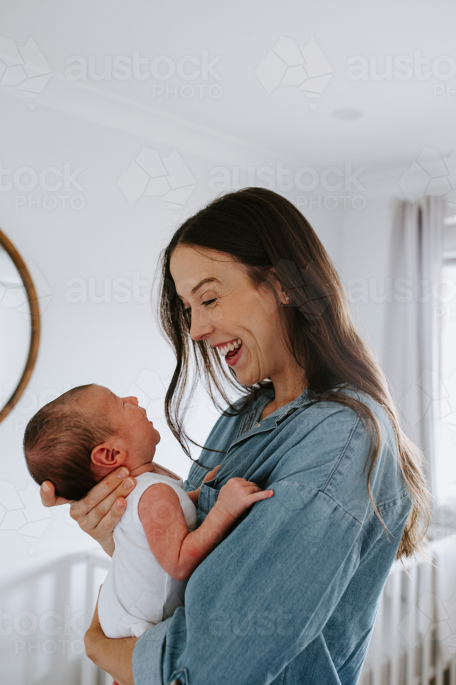 Happy young mother holding and looking at newborn baby boy - Australian Stock Image