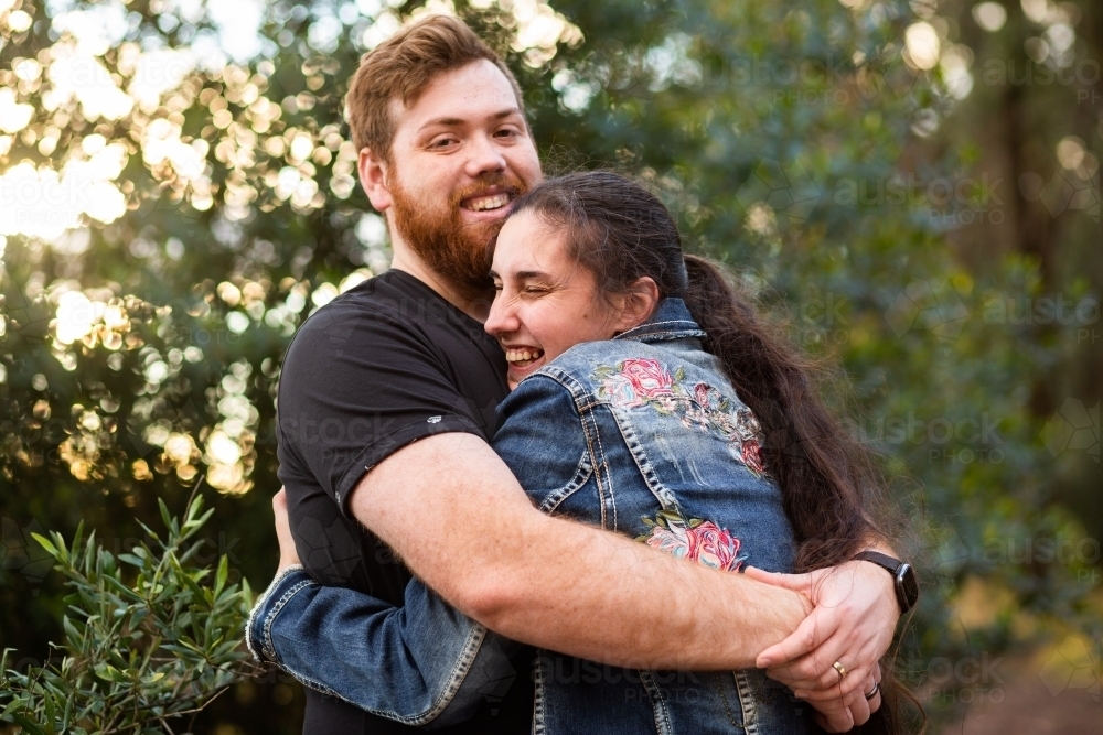 Happy young people hug with man looking at the camera - Australian Stock Image