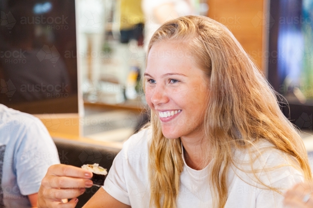 Happy young person trying sushi in shopping center - Australian Stock Image