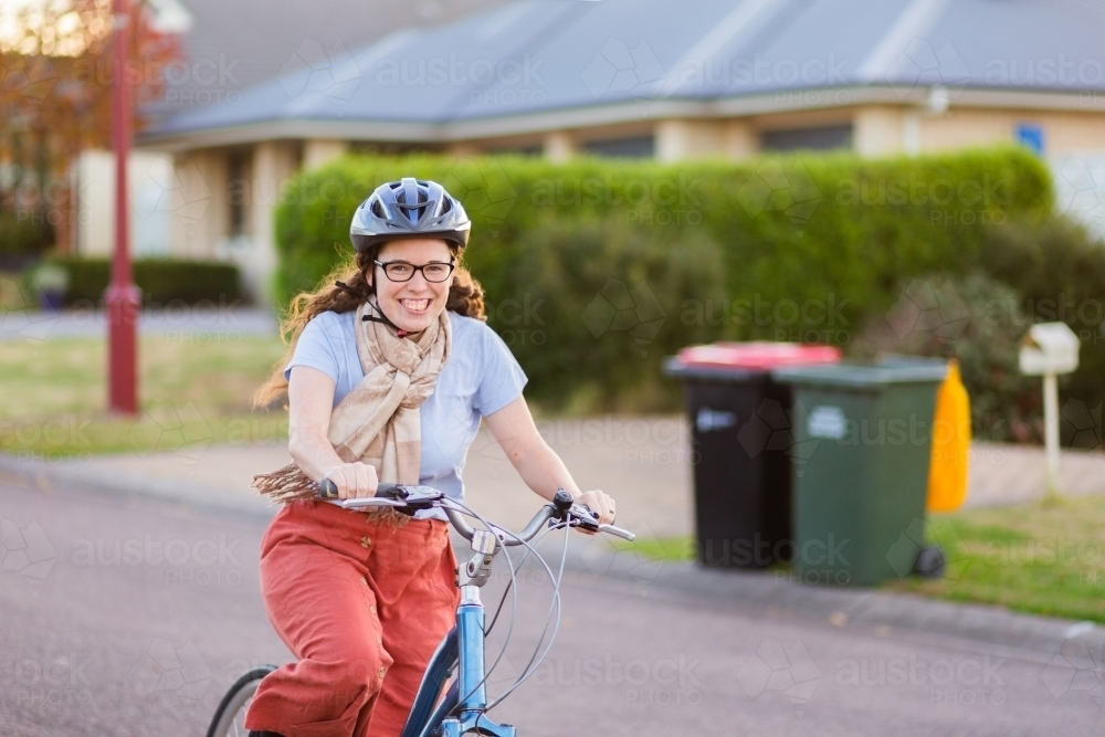 Happy young person wearing bicycle safety helmet with her pushbike - Australian Stock Image