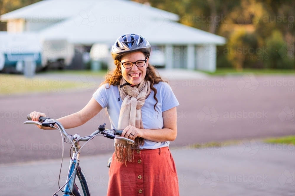 Happy young person wearing bicycle safety helmet with her pushbike - Australian Stock Image