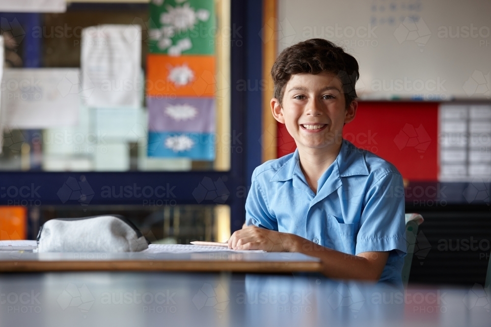 Happy young school boy in classroom - Australian Stock Image