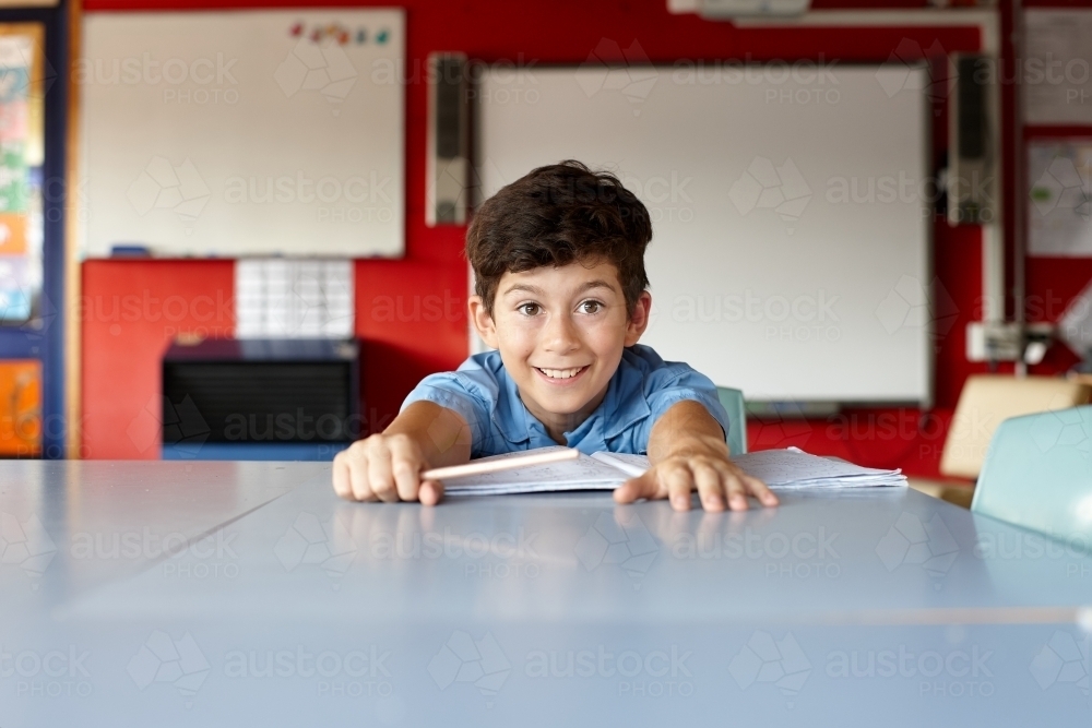 Happy young school boy in classroom - Australian Stock Image