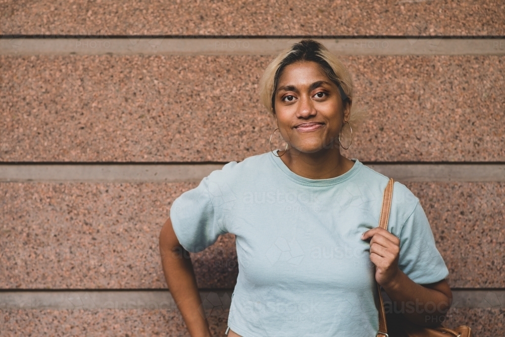 happy young student leading against wall - Australian Stock Image