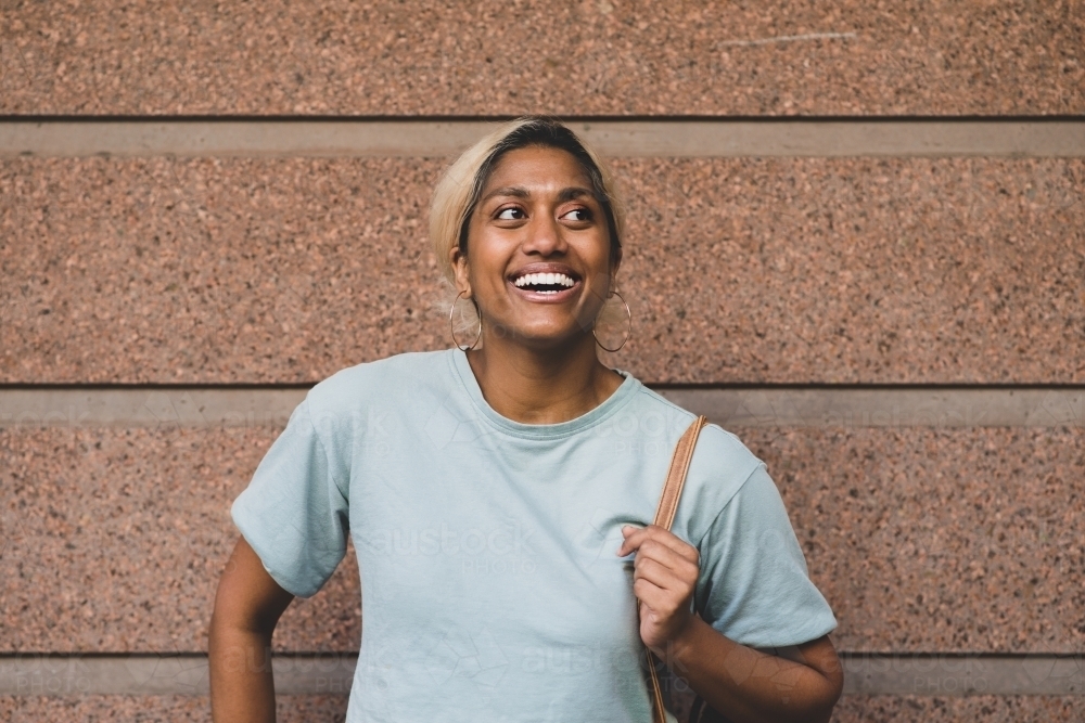 happy young student leading against wall - Australian Stock Image