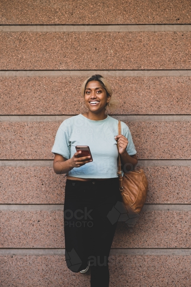 happy young student leading against wall - Australian Stock Image