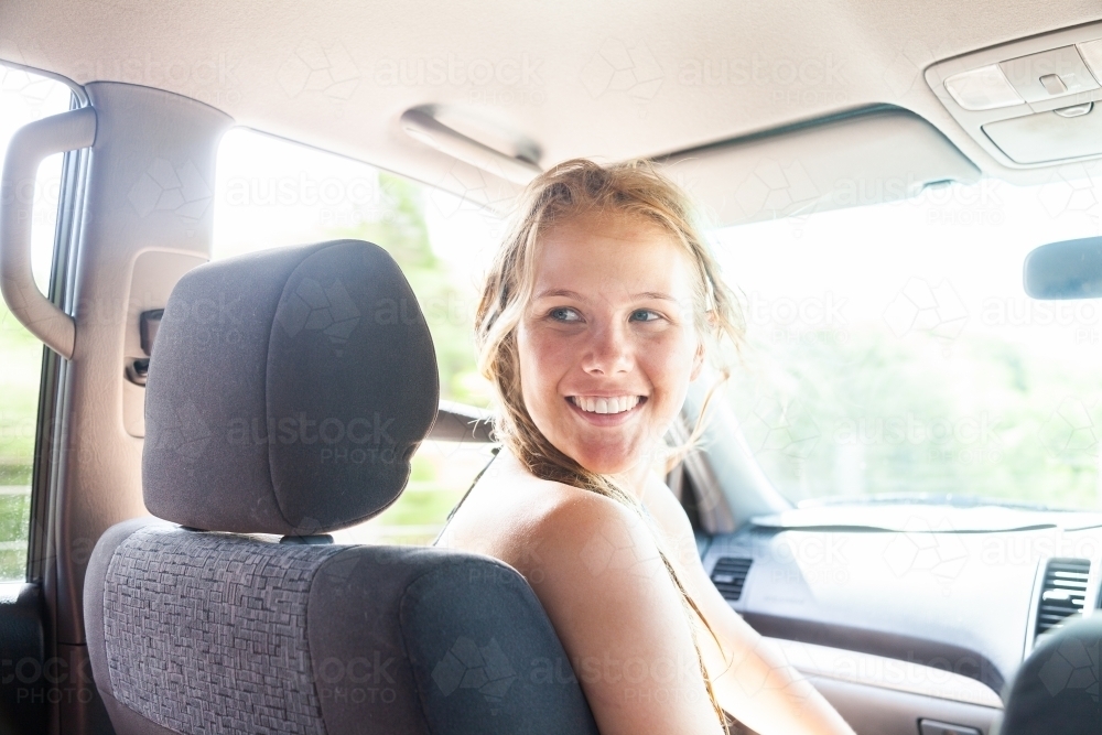 Happy young woman in passenger seat of car coming home from a beach day with friends - Australian Stock Image