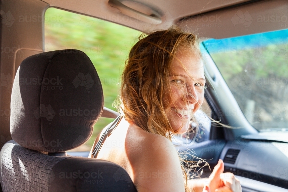 Happy young woman in passenger seat of car coming home from a beach day with friends - Australian Stock Image