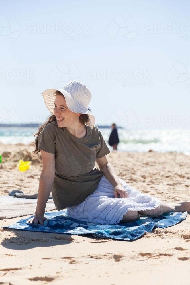Happy young woman in sunhat on bright beach - Australian Stock Image