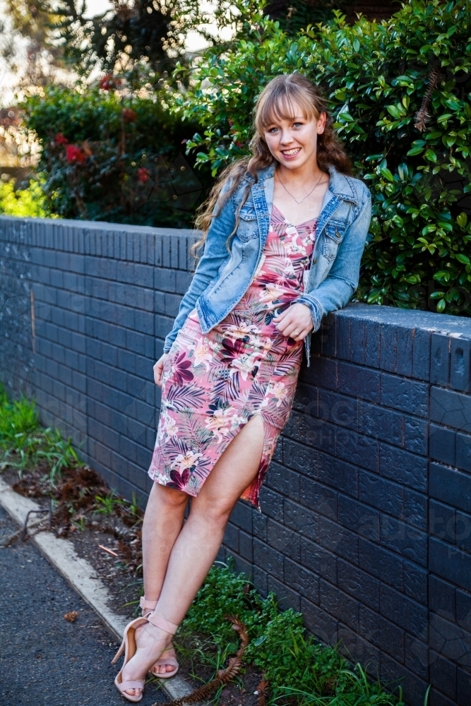 happy young woman leaning on blue wall - Australian Stock Image