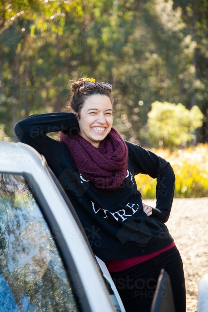 Happy young woman leaning on car laughing in winter - Australian Stock Image