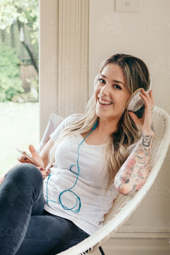 Happy young woman looking at camera with headphones - Australian Stock Image