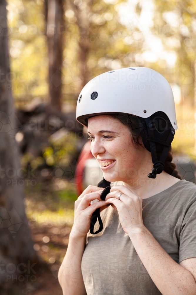 Happy young woman putting on horse riding safety helmet. - Australian Stock Image