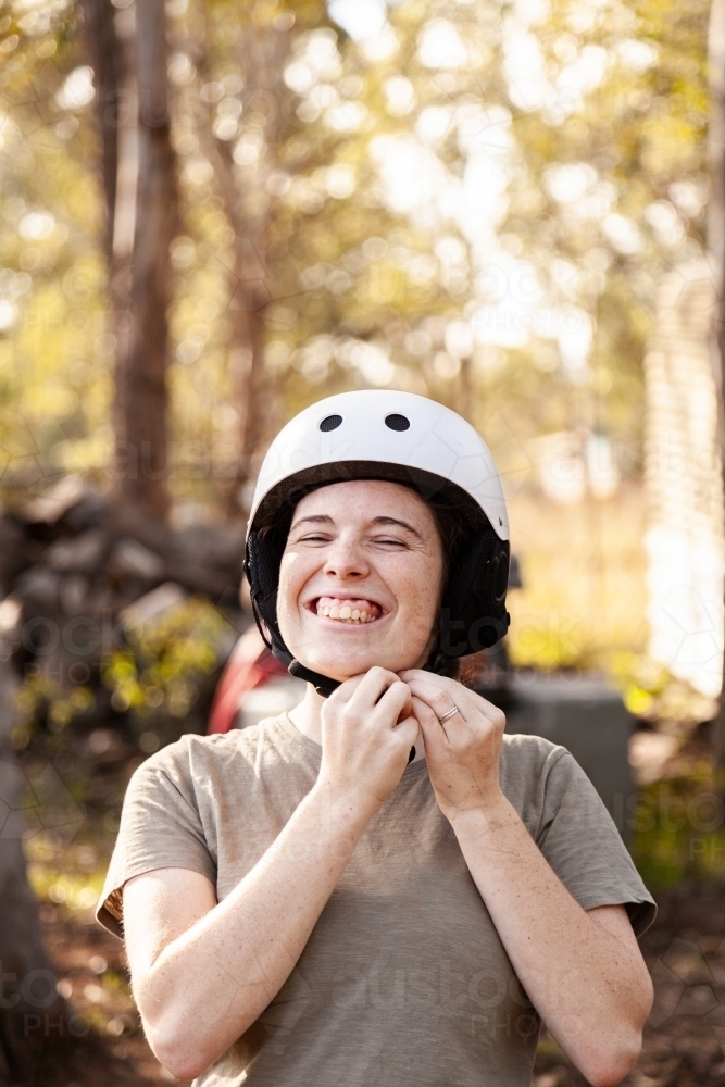 Happy young woman putting on horse riding safety helmet. - Australian Stock Image