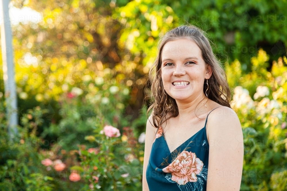 Happy young woman smiling in rose garden - Australian Stock Image