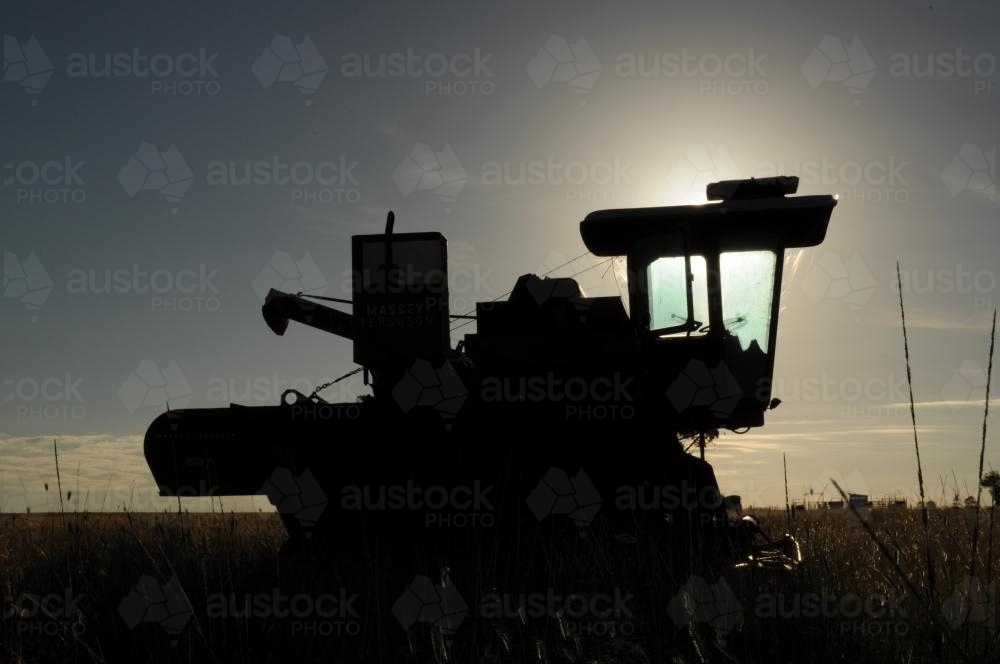 Harvester silhouetted against low light sky - Australian Stock Image