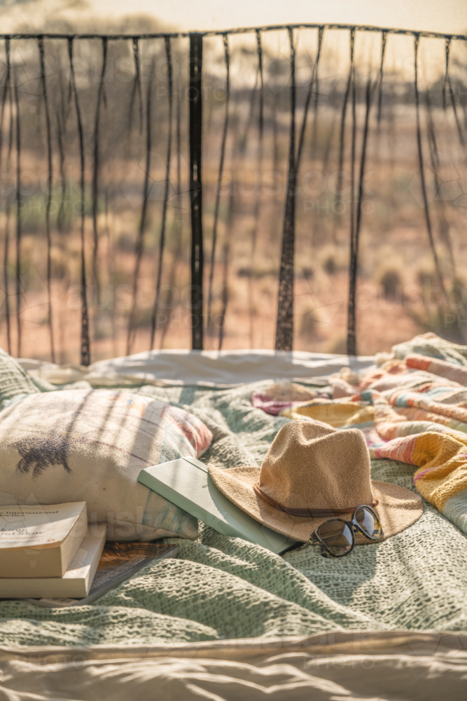 hat sunglasses and book laying on campervan bed in outback - Australian Stock Image