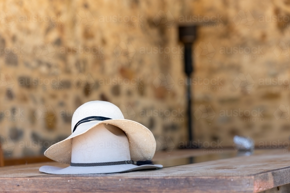 hats on wooden table with stone walls behind - Australian Stock Image