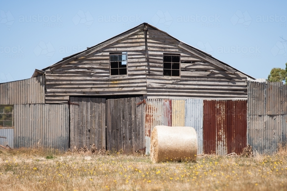 hay bale in front of an old barn - Australian Stock Image