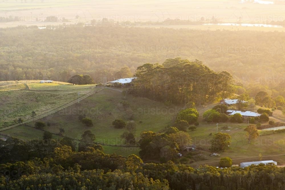 Haze over landscape of country farm house at sunset - Australian Stock Image