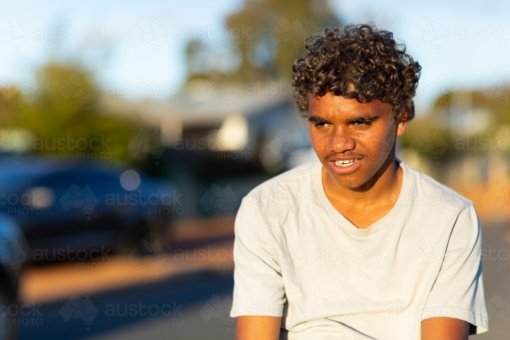 head and shoulders of aboriginal boy outdoors in town - Australian Stock Image