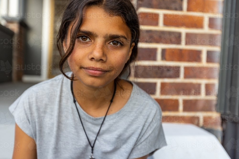 head and shoulders of Aboriginal girl with intense stare - Australian Stock Image