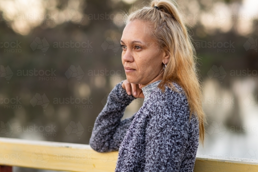 head and shoulders of aboriginal woman with blonde hair side on to camera - Australian Stock Image