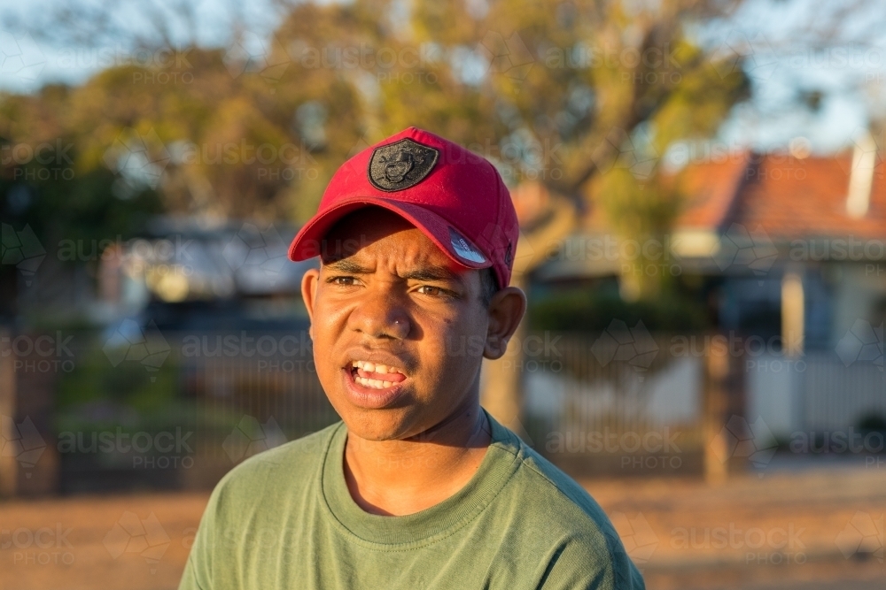head and shoulders of adolescent wearing red baseball cap - Australian Stock Image