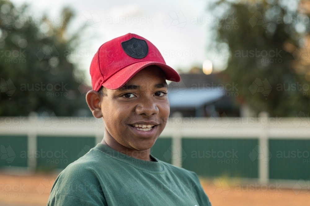 head and shoulders of adolescent wearing red baseball cap - Australian Stock Image