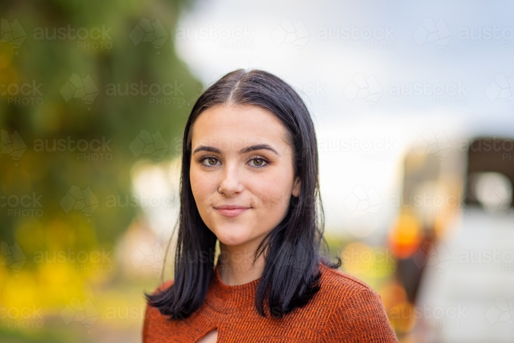 head and shoulders of dark-haired teenage girl standing outdoors - Australian Stock Image