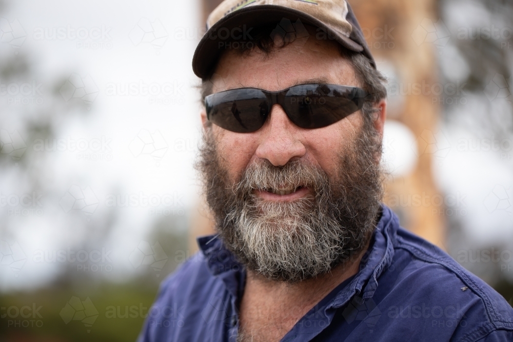 head and shoulders of hairy bearded man wearing dark sunglasses - Australian Stock Image