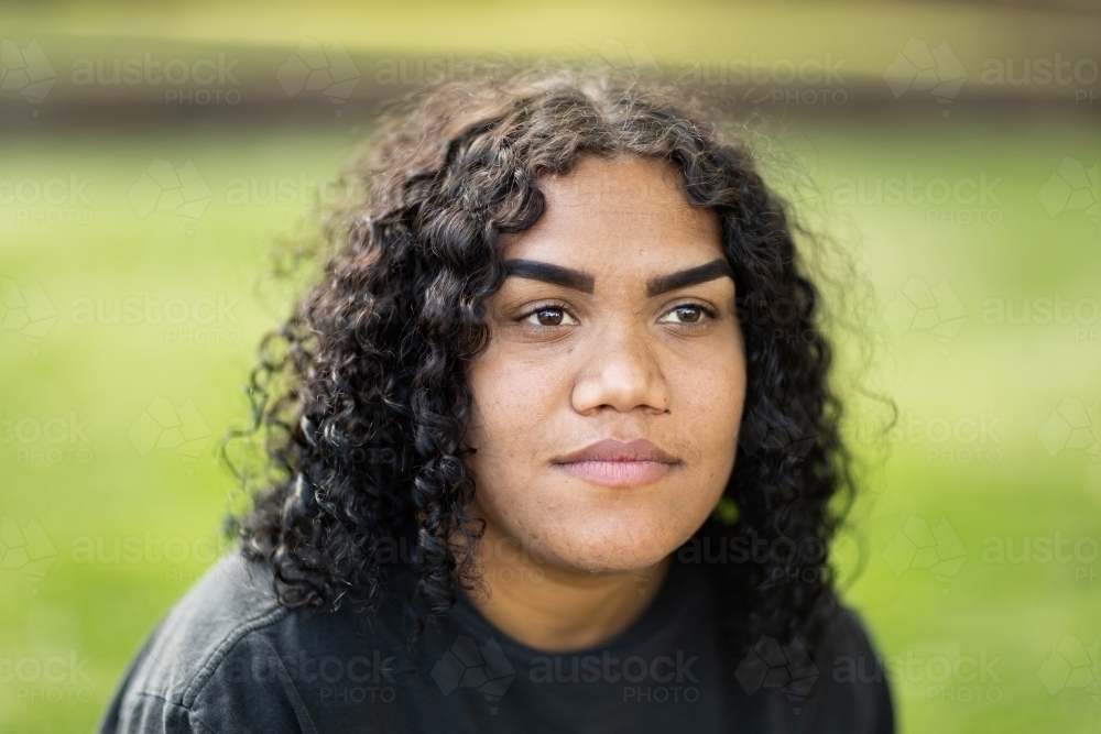 head and shoulders of indigenous girl with curly hair and blurry background - Australian Stock Image