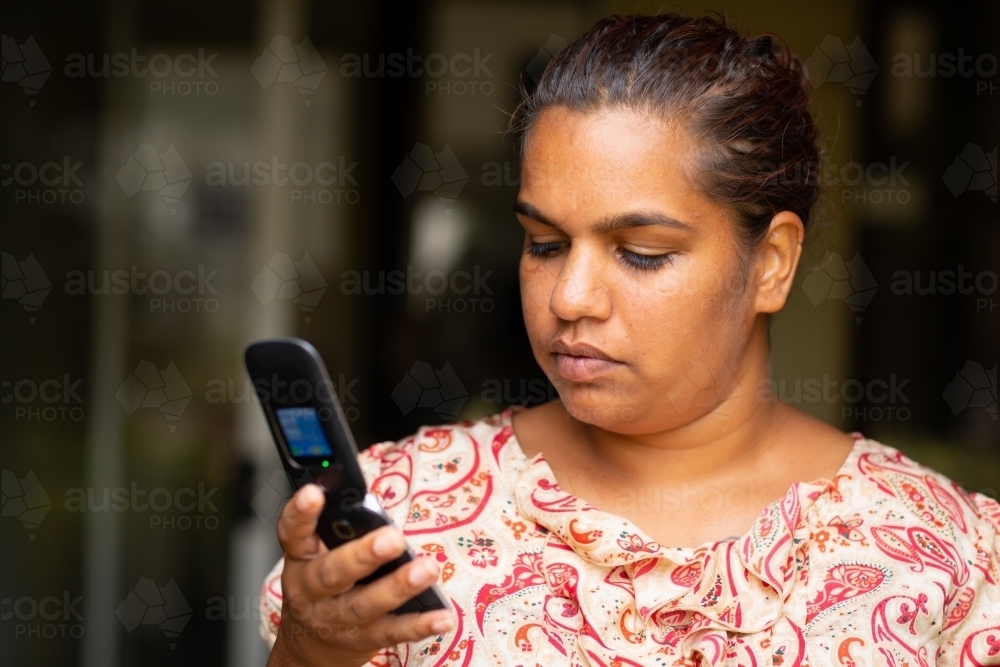 head and shoulders of lady looking at flip phone - Australian Stock Image