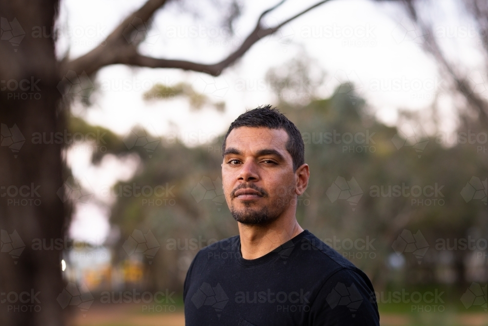 head and shoulders of man in black squinting - Australian Stock Image