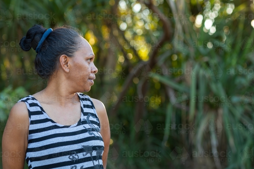 head and shoulders of mature woman in profile wearing striped singlet outdoors - Australian Stock Image