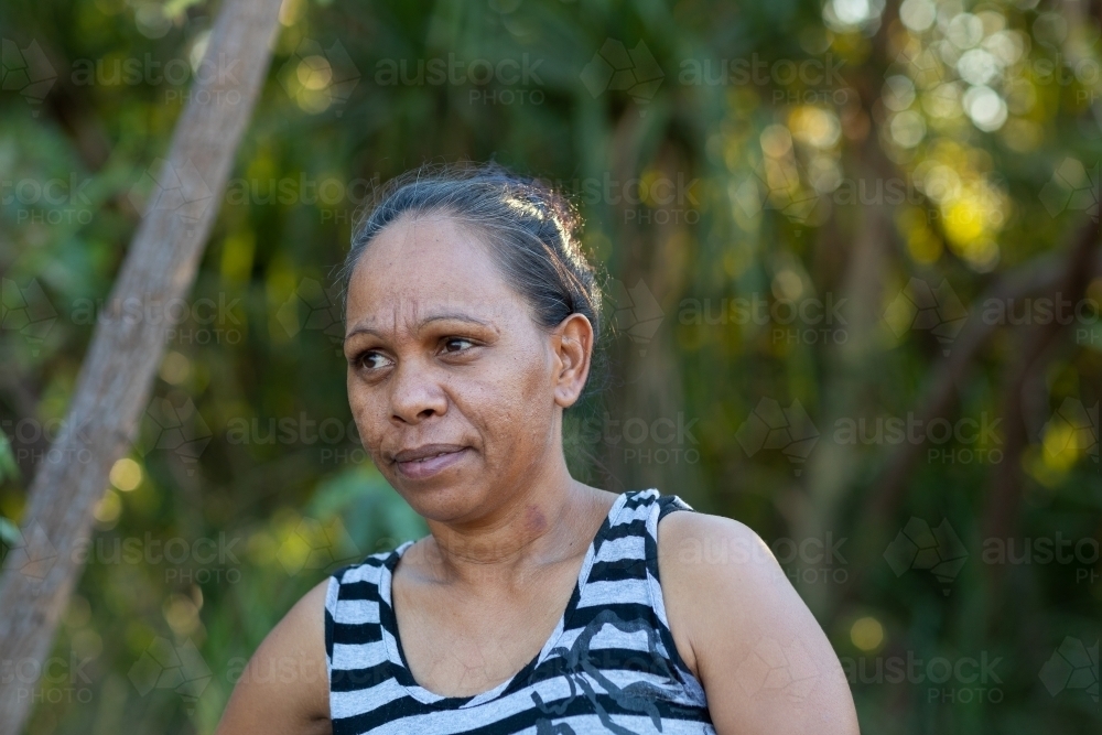 head and shoulders of mature woman wearing striped singlet outdoors - Australian Stock Image