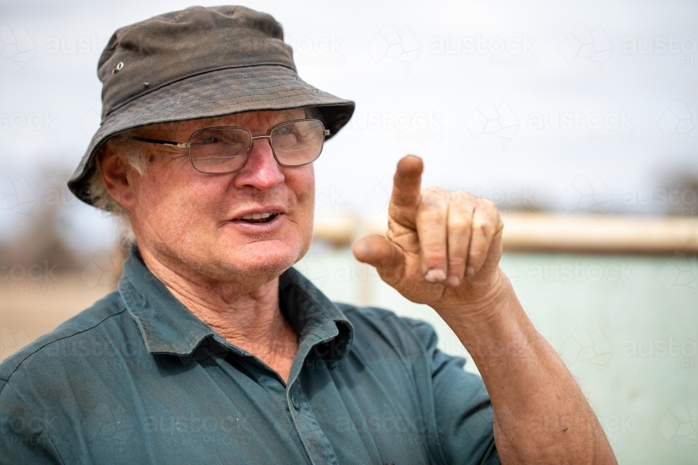 head and shoulders of older manual worker pointing index finger - Australian Stock Image