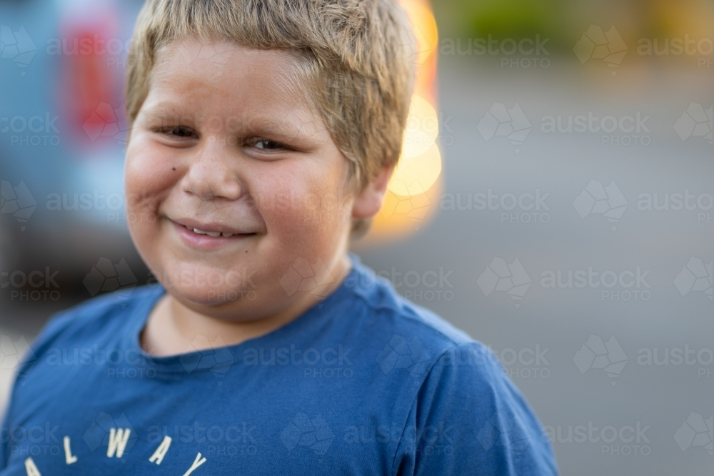 head and shoulders of one boy in blue shirt smiling - Australian Stock Image