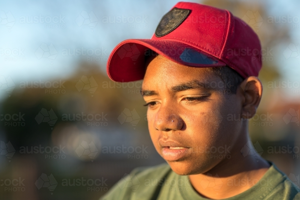 head and shoulders of teen boy wearing red baseball cap - Australian Stock Image