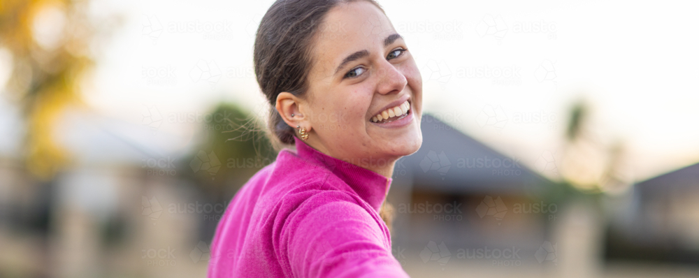 head and shoulders of teen girl looking back towards camera over her shoulder - Australian Stock Image