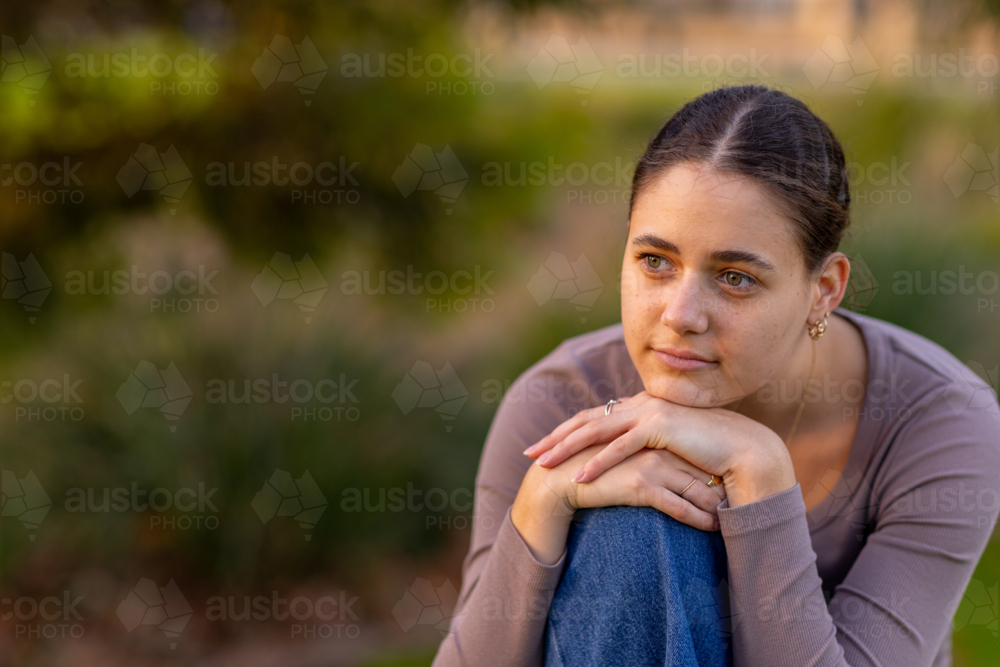 head and shoulders of teen girl looking off into distance with copy space and blurry background - Australian Stock Image