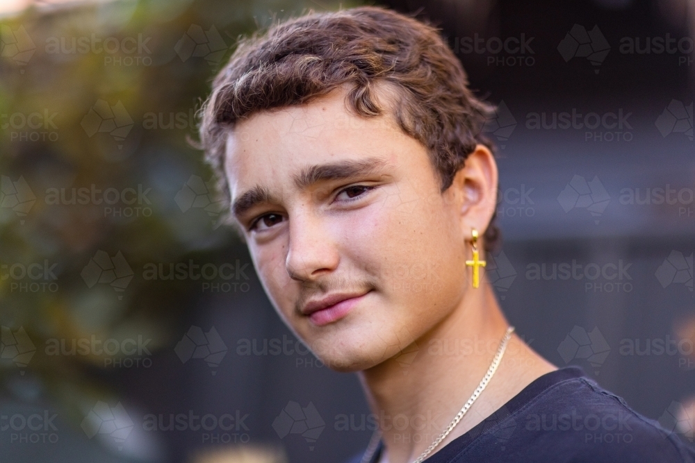 head and shoulders of teenage boy looking at camera with tilted head - Australian Stock Image